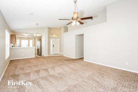 a spacious living room with carpet and a ceiling fan