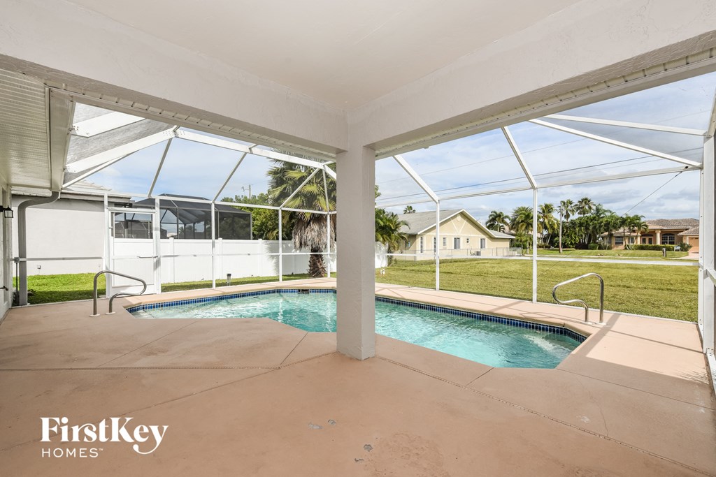 a large pool and spa in the back of a house with glass doors