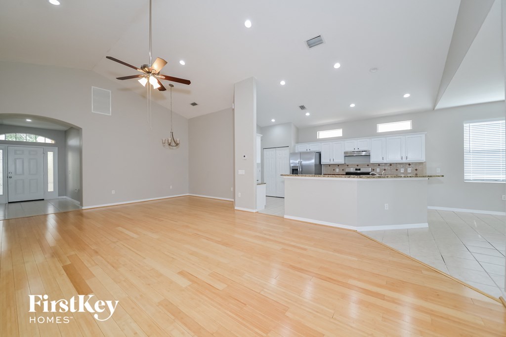 A spacious room with wooden floors and a ceiling fan.