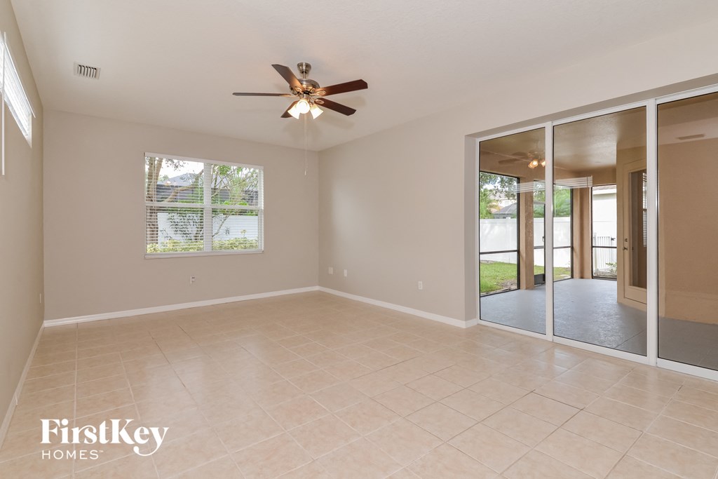 A spacious room with a ceiling fan and sliding glass doors leading to a patio.