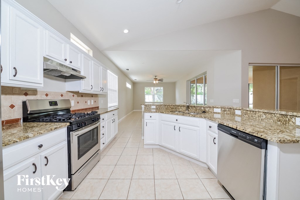 A kitchen with white cabinets and granite countertops.