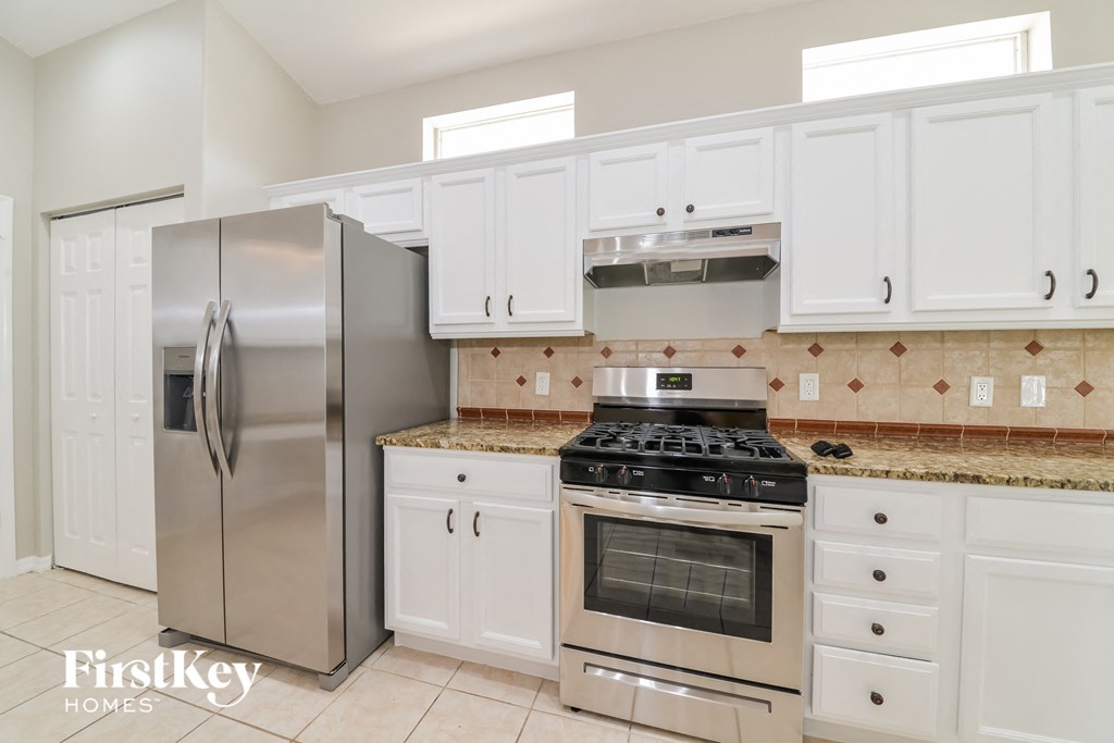 A kitchen with a stainless steel refrigerator and white cabinets.