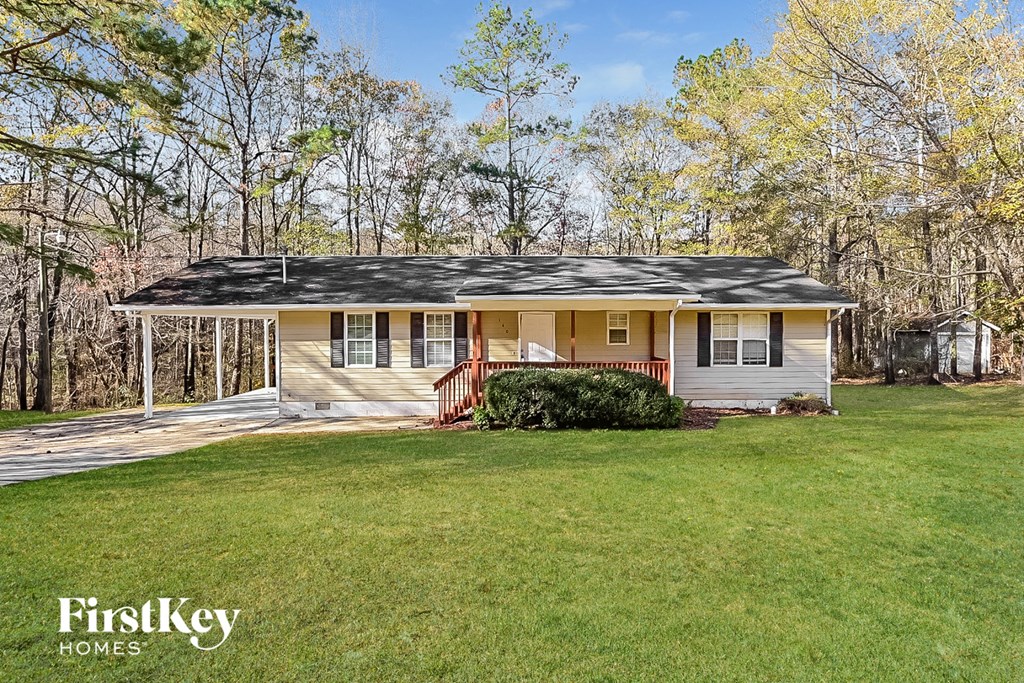 a small yellow house with a porch and a grassy yard