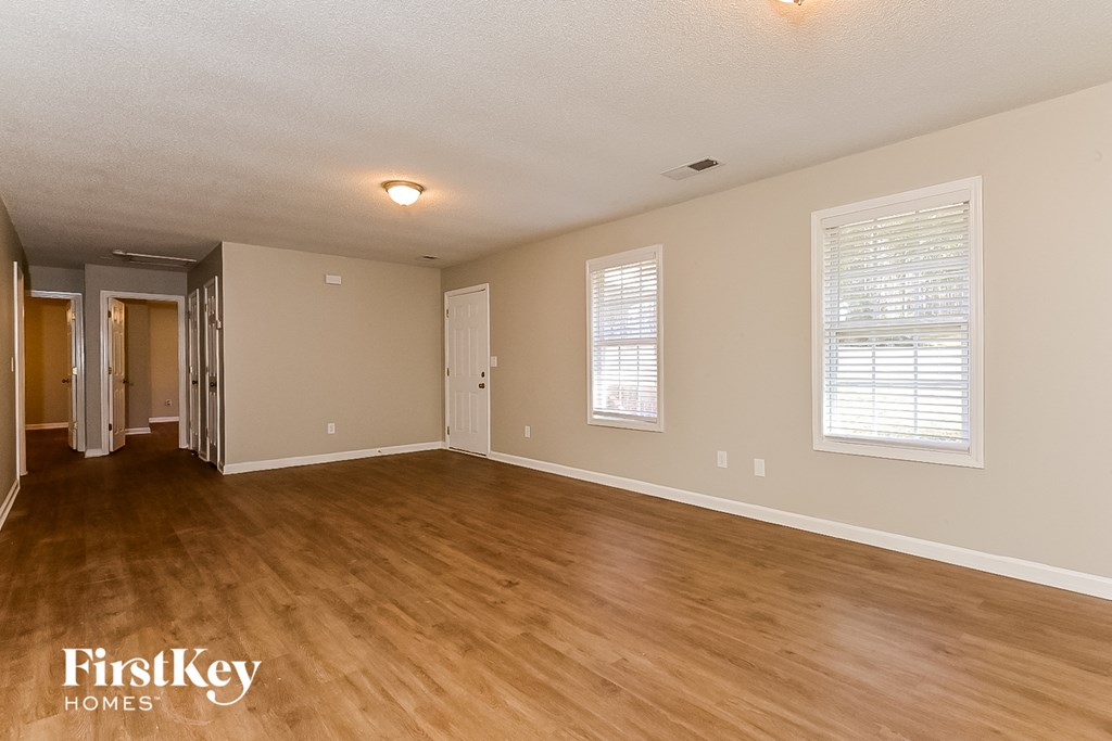 the living room and dining room of an empty house with wood flooring