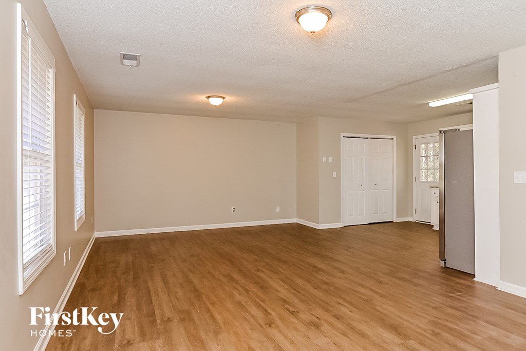 the living room and dining room of an empty house with wood flooring