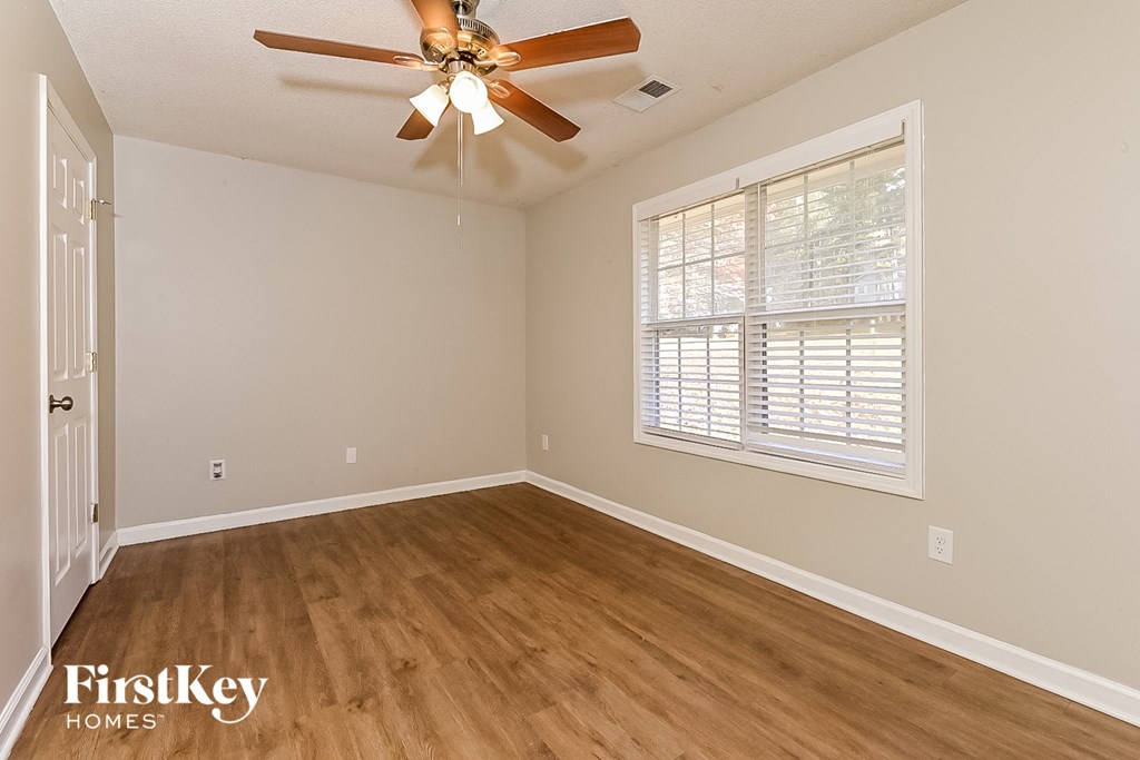 the living room of an empty home with wooden floors and a ceiling fan