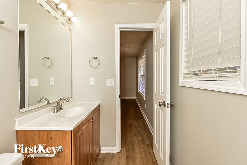 a bathroom with a sink and a mirror and a hallway