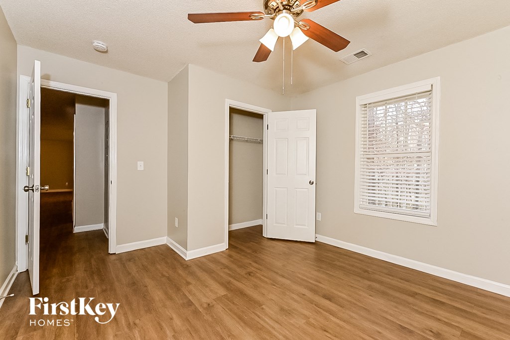 an empty living room with a ceiling fan and a door to a closet
