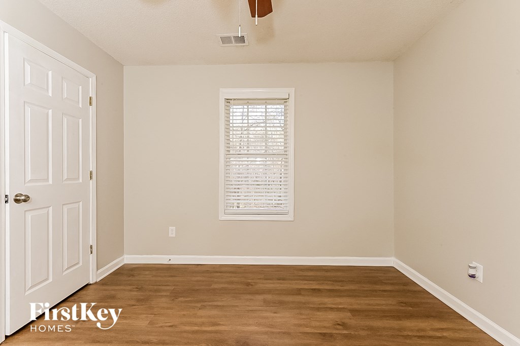 a bedroom with a wooden floor and a window and a white door
