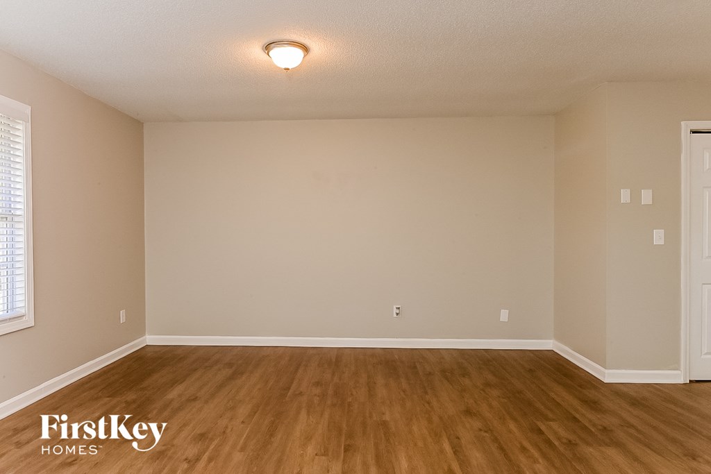 the spacious living room with wood flooring and white walls