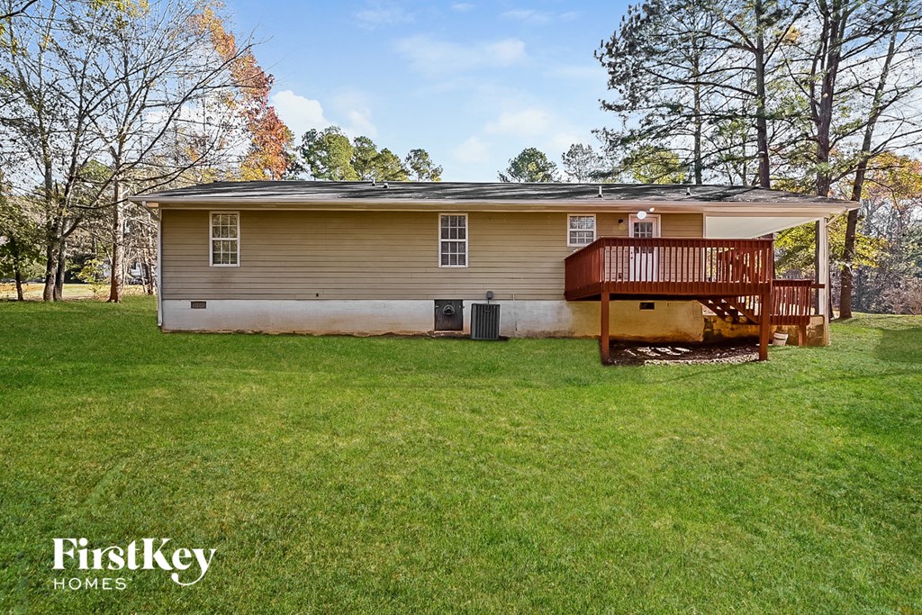 a small brown house with a deck on a lawn