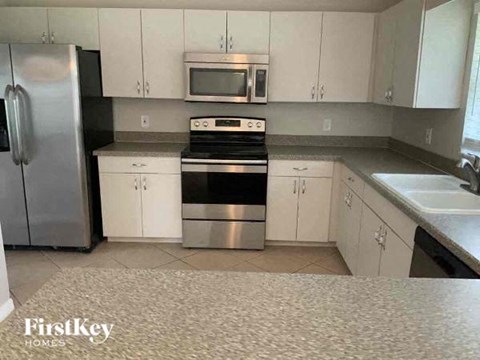 A kitchen with white cabinets and a stainless steel refrigerator.
