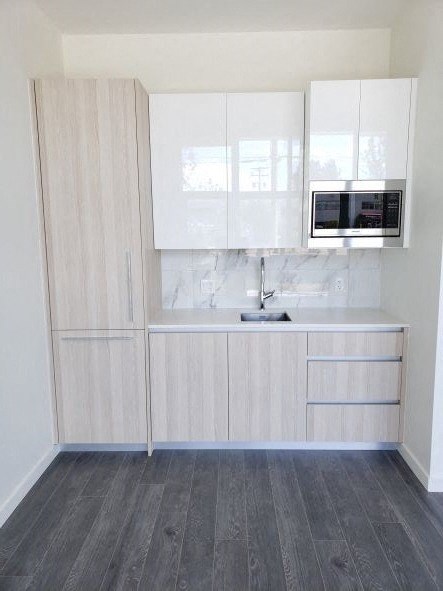 A kitchen with white cabinets and a marble countertop.