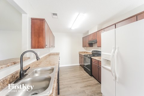 A kitchen with a sink, refrigerator, and stove.