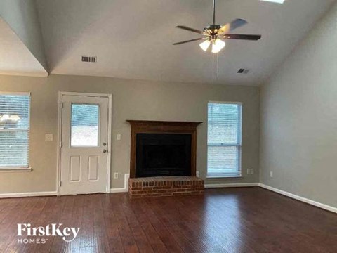 A living room with a fireplace and a ceiling fan.