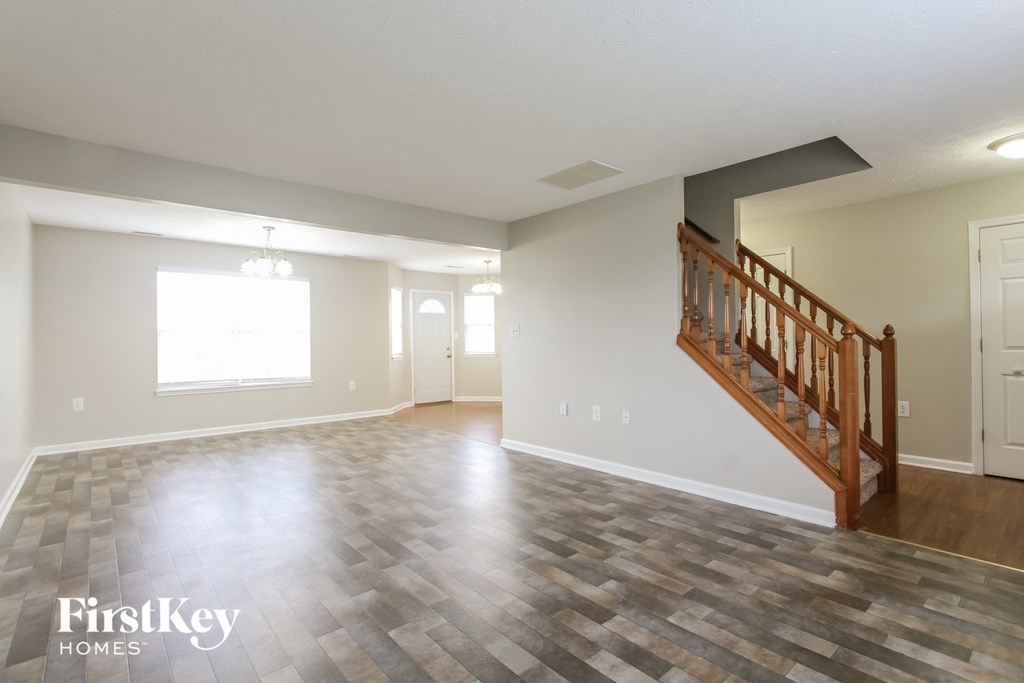 A spacious room with a wooden staircase and a tiled floor.