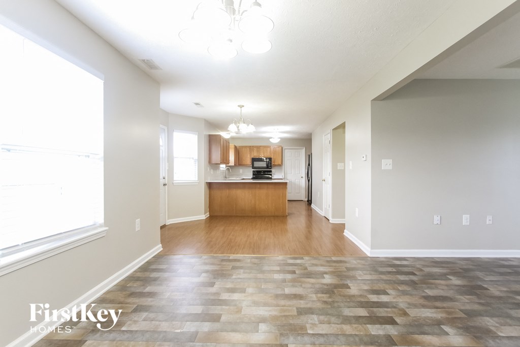 A spacious living room with a kitchen in the background.