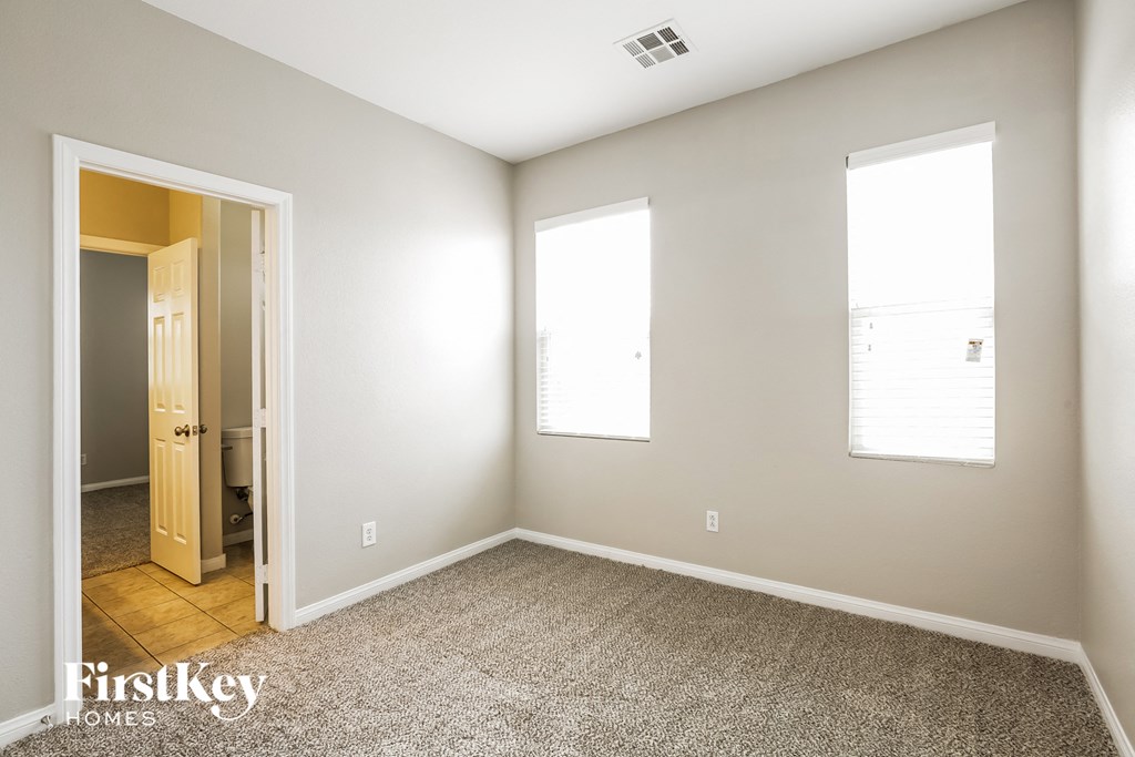 a room with carpet and two windows and a door