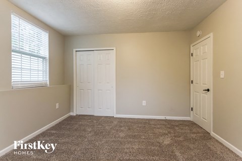 a carpeted living room with two doors and a window