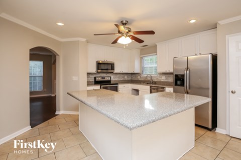 a white kitchen with a large island and stainless steel appliances