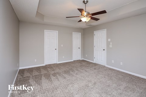 the spacious living room with ceiling fan and carpet
