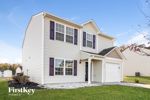 a white house with purple window shutters and a white garage