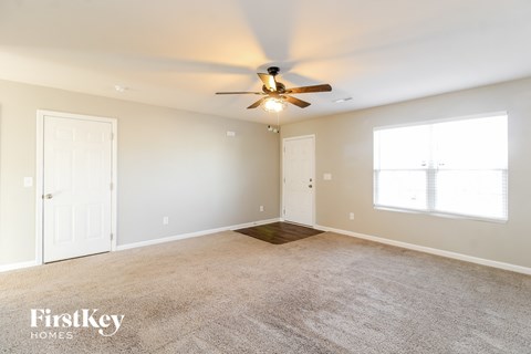 a living room with carpet and a ceiling fan