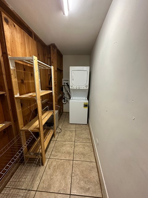 A kitchen with a white fridge and wooden shelves.