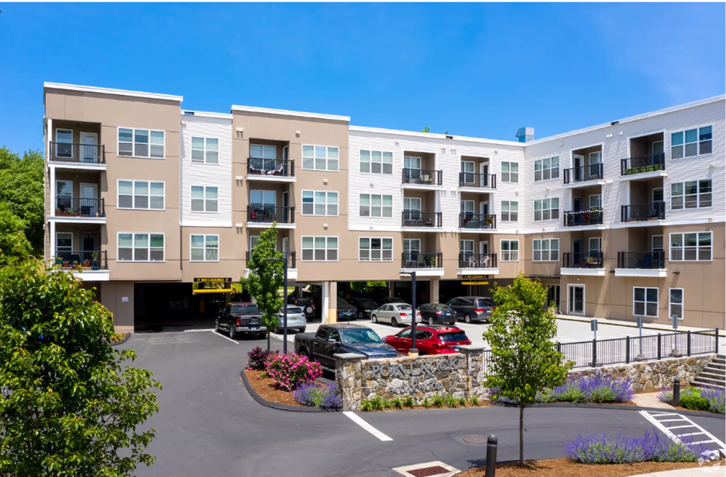 an exterior view of an apartment building with cars parked in a parking lot