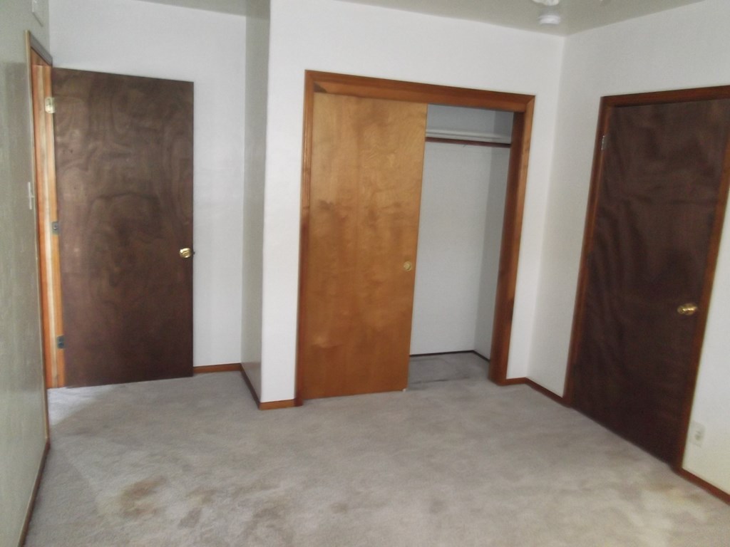 an empty room with three doors and a carpeted floor
