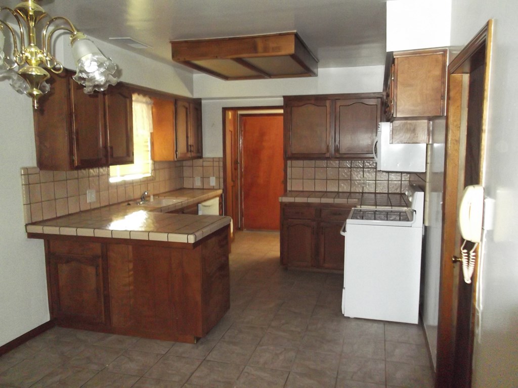 an empty kitchen with wooden cabinets and white appliances