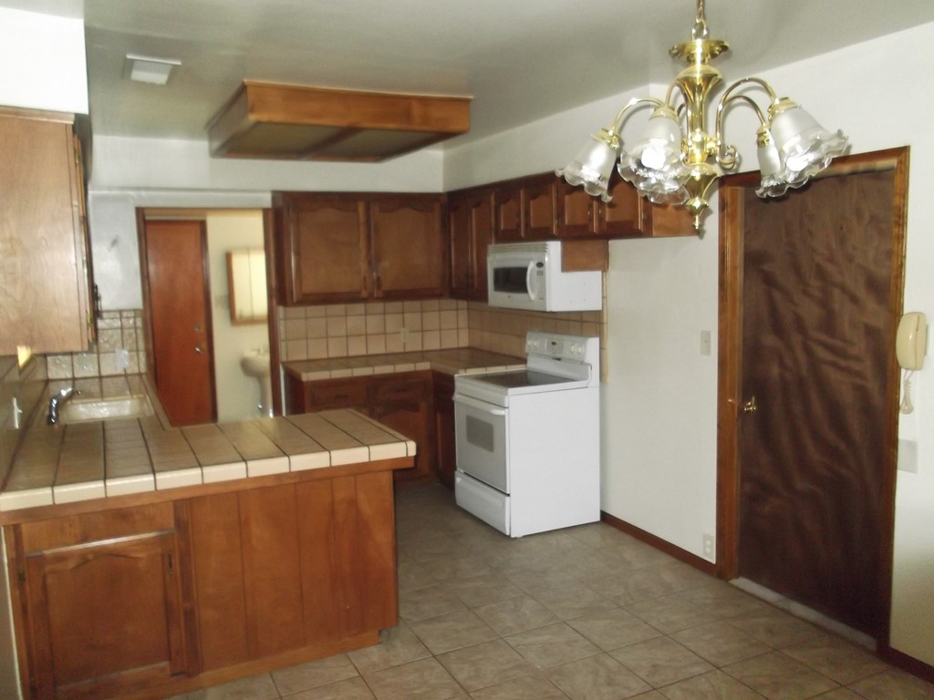 an empty kitchen with wooden cabinets and a white stove and refrigerator