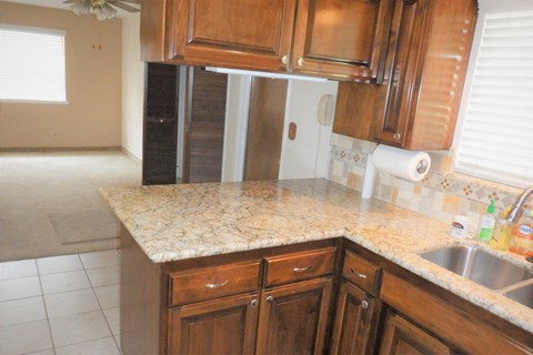 a kitchen with a marble counter top and wooden cabinets