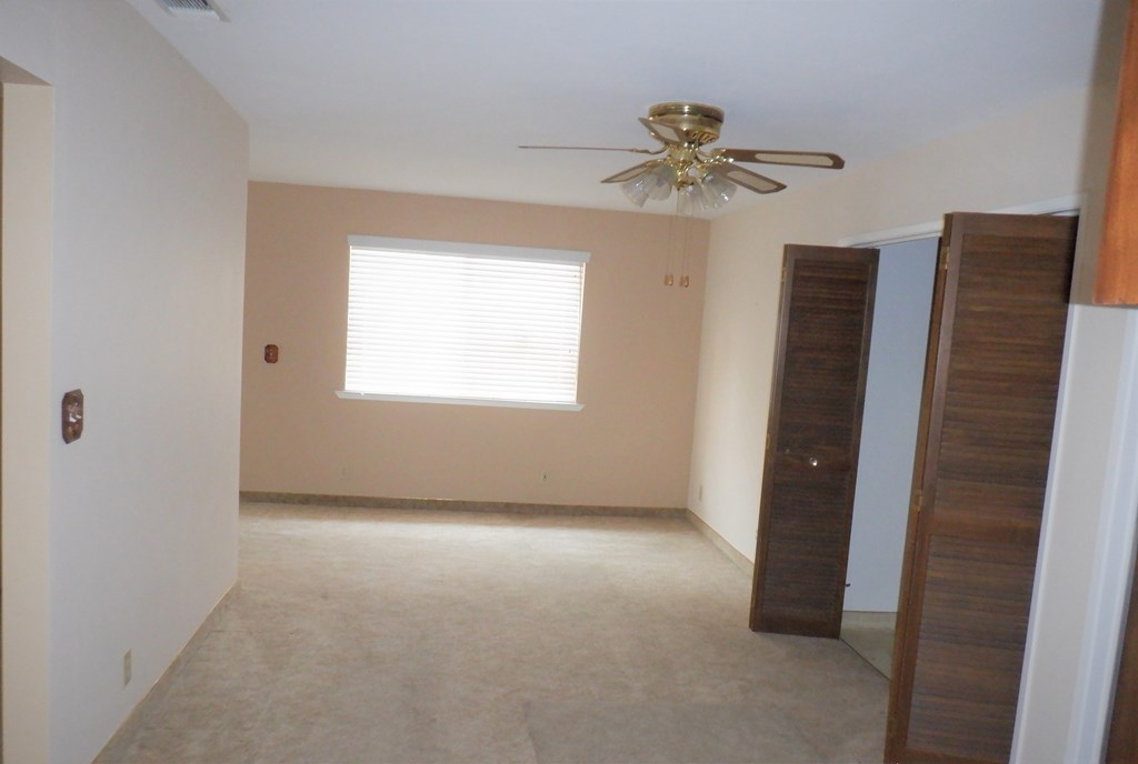 an empty living room with a ceiling fan