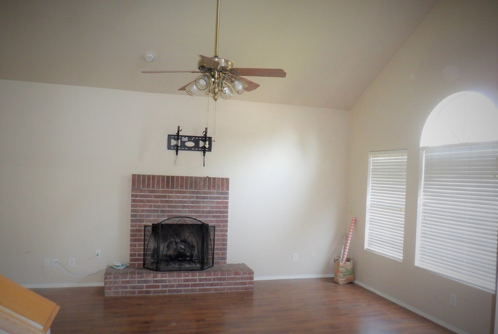 a living room with a brick fireplace and a ceiling fan