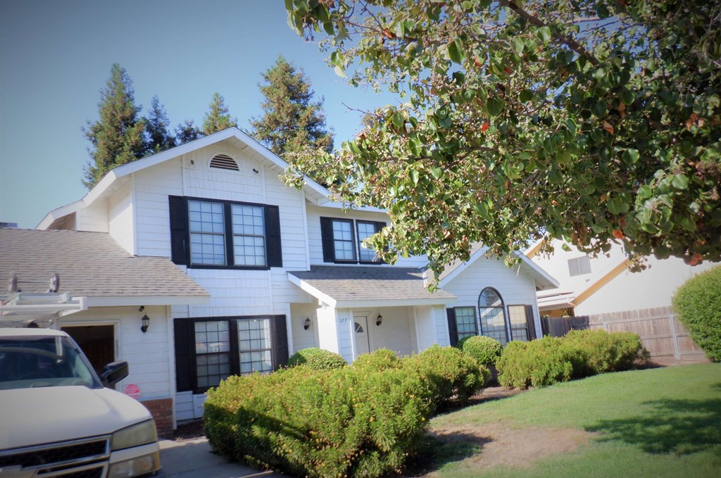 a white house with black windows and a car parked in front of it