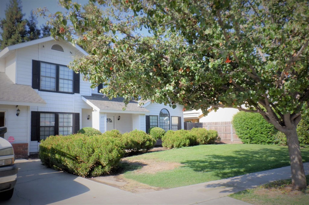 a white house with a yard and a tree