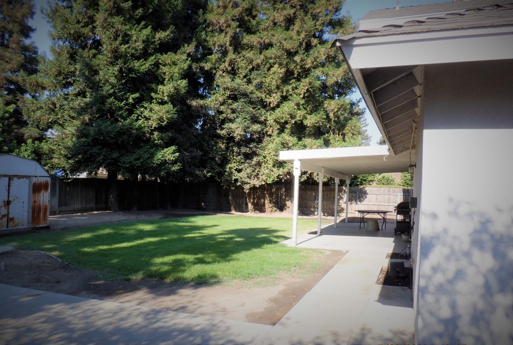 the backyard of a house with a lawn and a picnic table