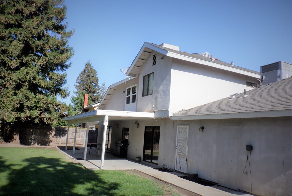 the front of a white house with a driveway and a tree