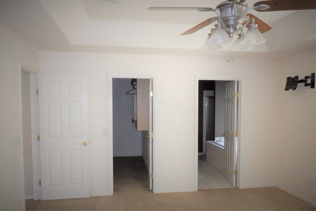 a bedroom with a ceiling fan and a closet and a bathroom