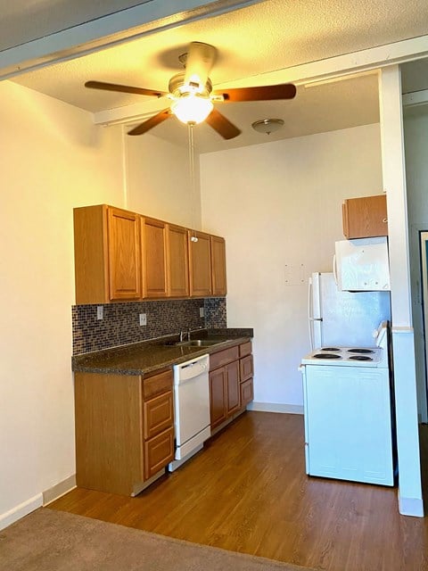 an empty kitchen with a ceiling fan and a refrigerator