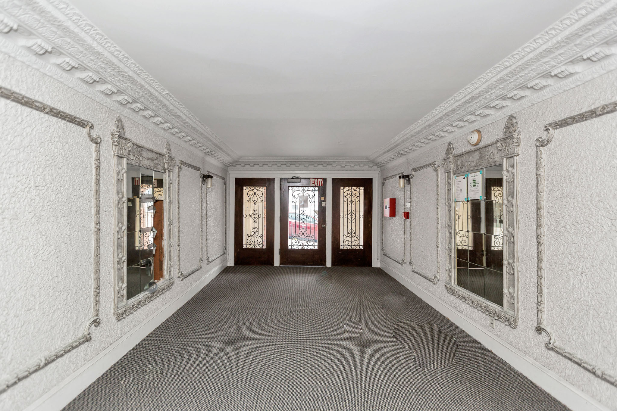 A long hallway with white walls and a grey floor.