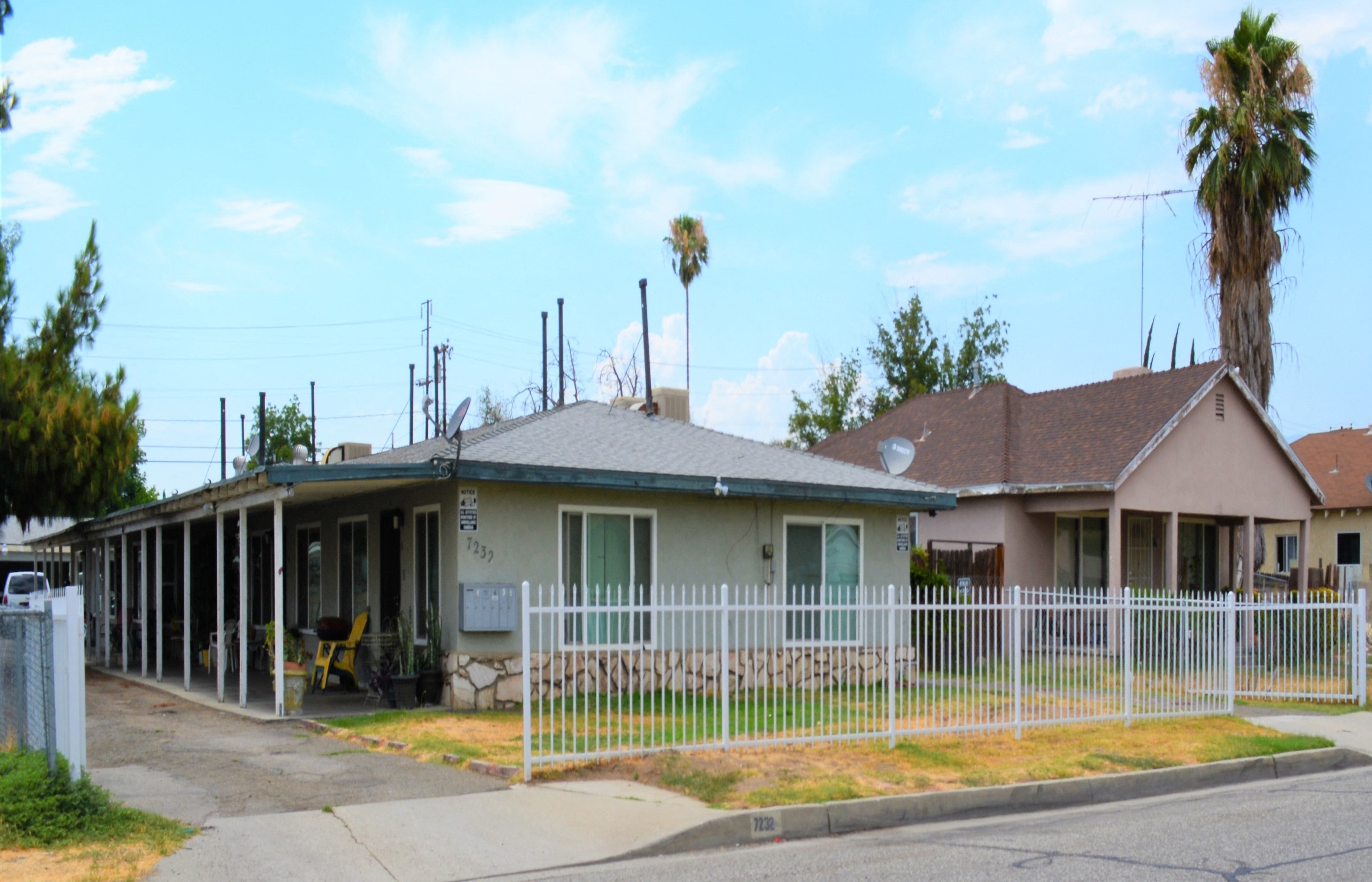 a house with a white fence and a palm tree