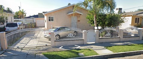a house with a car behind a white fence