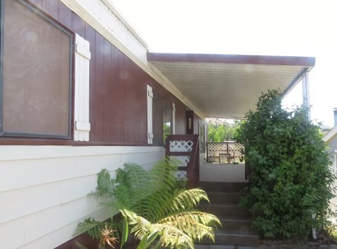 A house with a white wall and a brown roof with a staircase leading to the door.