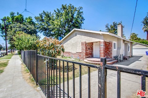 a small house with a fence and a sidewalk in front of it