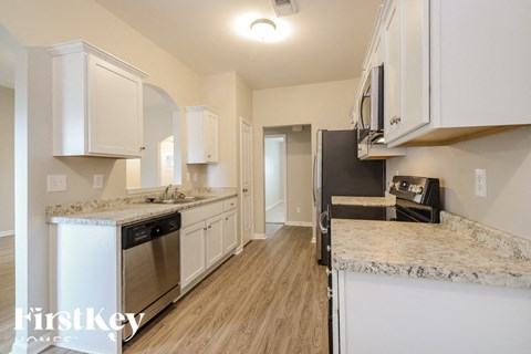 A kitchen with white cabinets and a granite countertop.