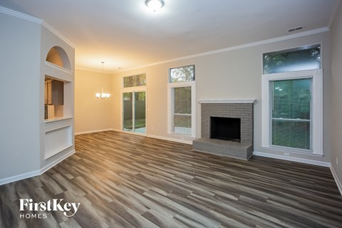 A spacious living room with a fireplace and wood flooring.