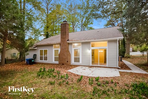 A house with a brown door and a chimney is surrounded by trees.