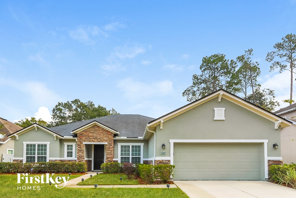a beige house with a garage door and a lawn